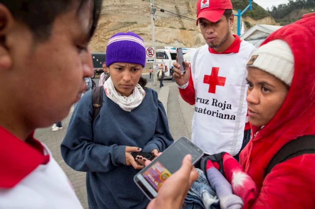 Red Cross volunteers help Ecuadorian migrants to contact their families by offering a free call service with smartphones